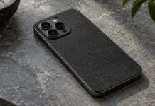 Kumaş dokulu arka yüzeye sahip koyu renkli bir akıllı telefonun masada duruşu